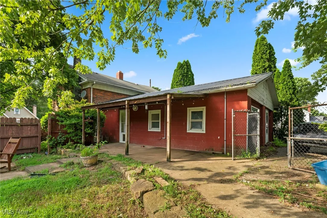 Back of property featuring a metal roof, concrete block siding, a gate, and a patio area