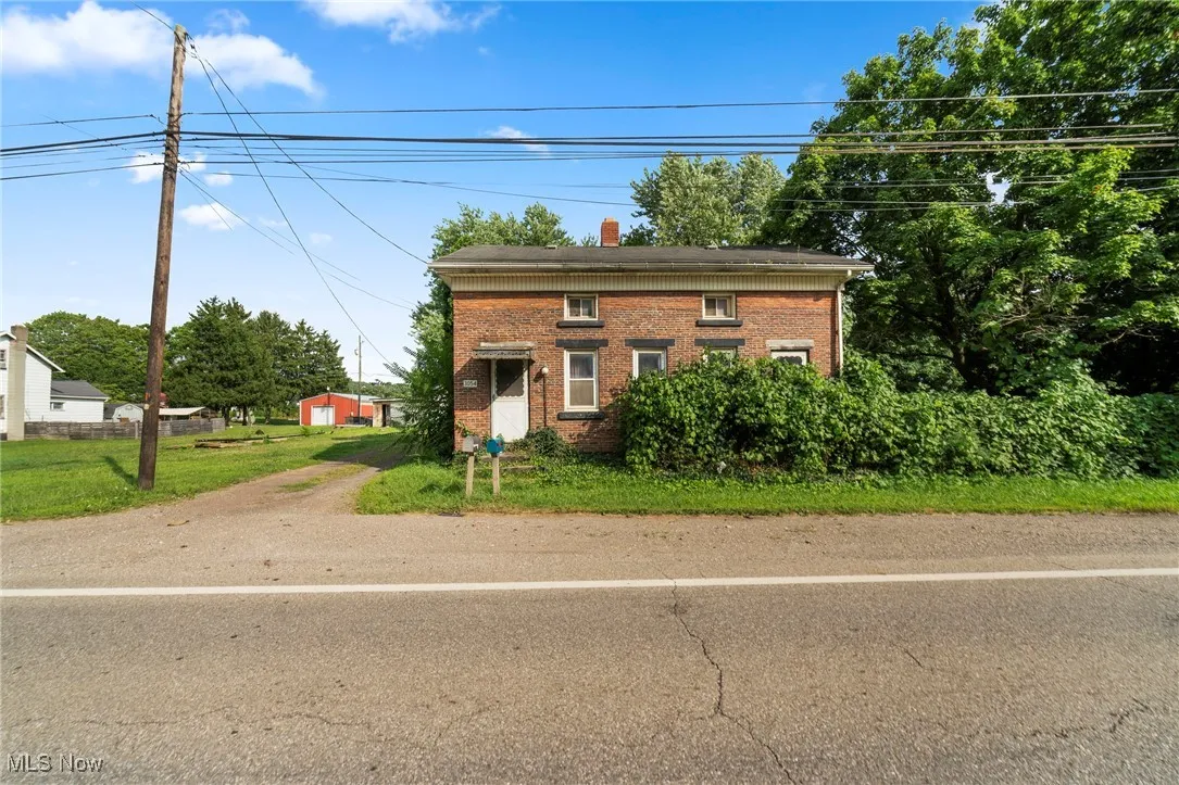 Colonial-style house with a chimney, brick siding, and an outdoor structure