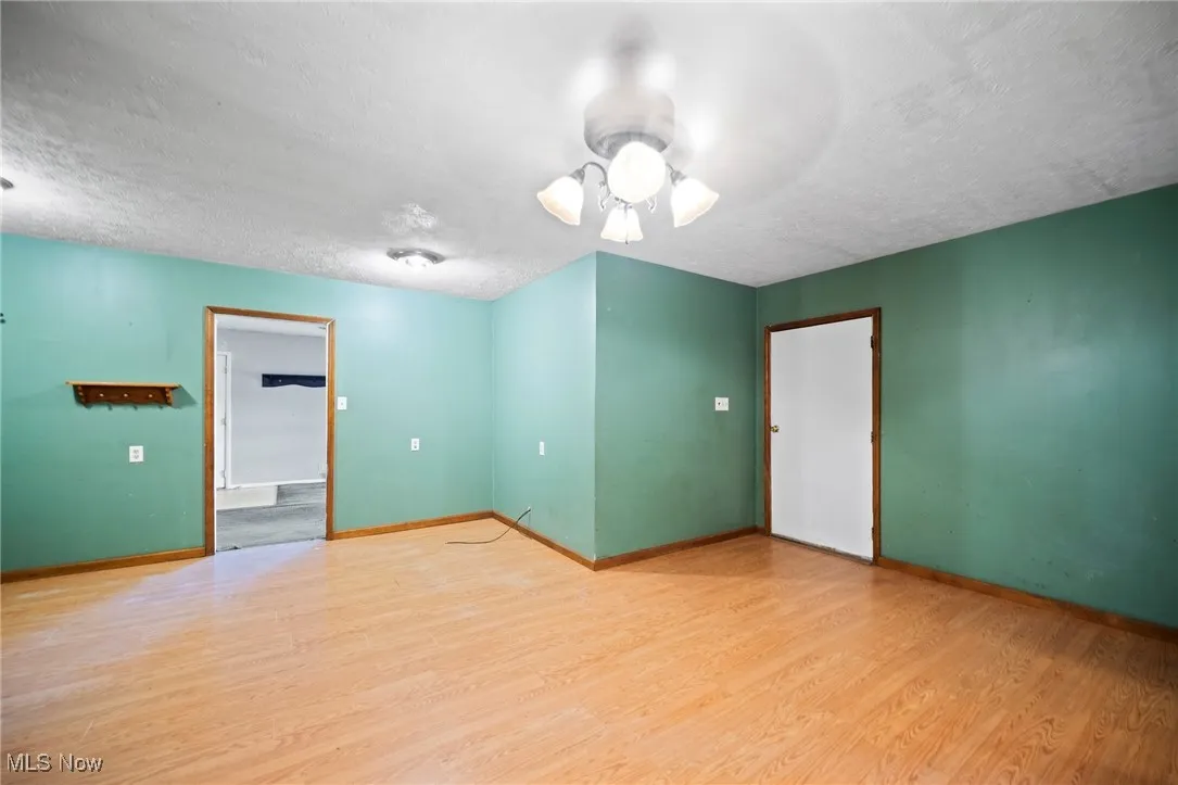Unfurnished room featuring a textured ceiling, a ceiling fan, and wood finished floors
