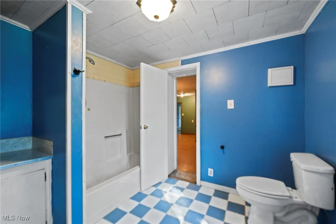 Bathroom with ornamental molding, tile patterned floors, shower / tub combination, and vanity