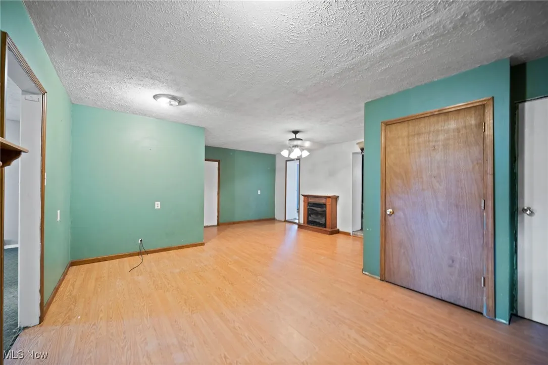 Unfurnished living room featuring a fireplace, wood finished floors, and a textured ceiling