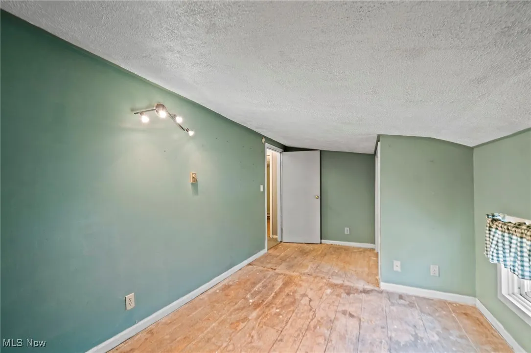 Empty room featuring a textured ceiling and wood finished floors