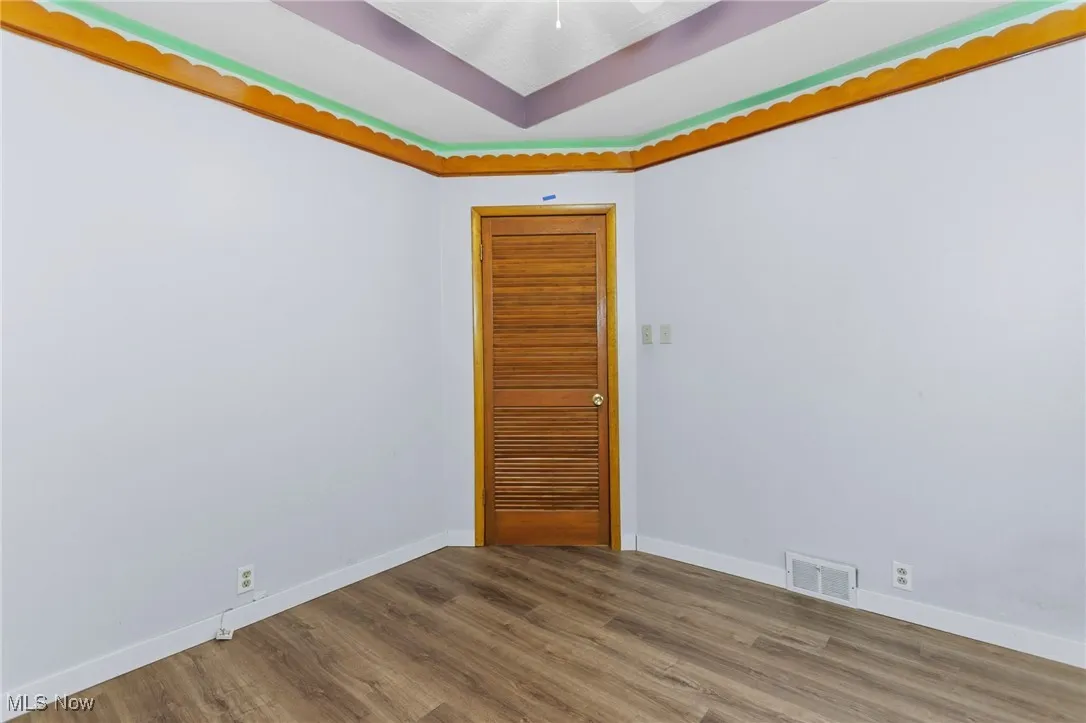 Unfurnished room with wood finished floors and a tray ceiling