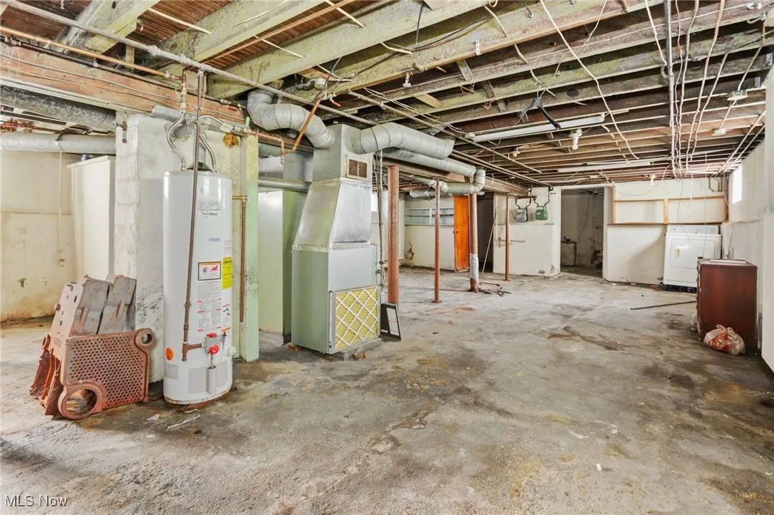 Unfinished basement featuring gas water heater, heating unit, and washer and clothes dryer