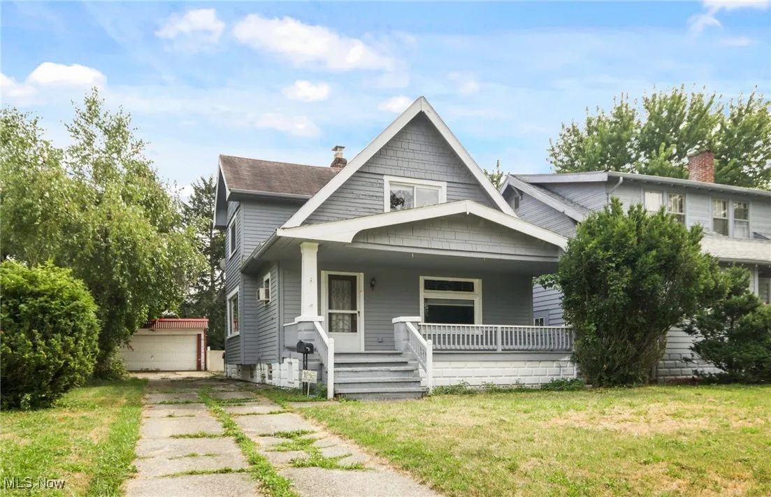 Bungalow featuring a chimney, covered porch, an outbuilding, a front lawn, and a detached garage