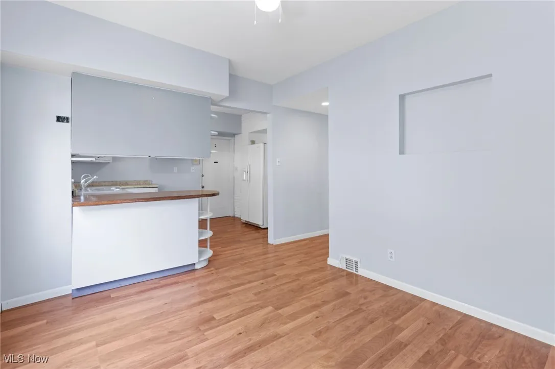Kitchen featuring light wood-style flooring, white fridge with ice dispenser, and dark countertops