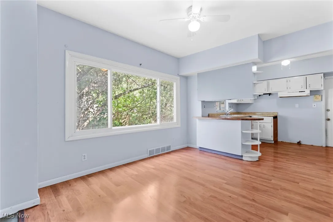 Kitchen featuring light wood-type flooring, white cabinets, a ceiling fan, and open shelves