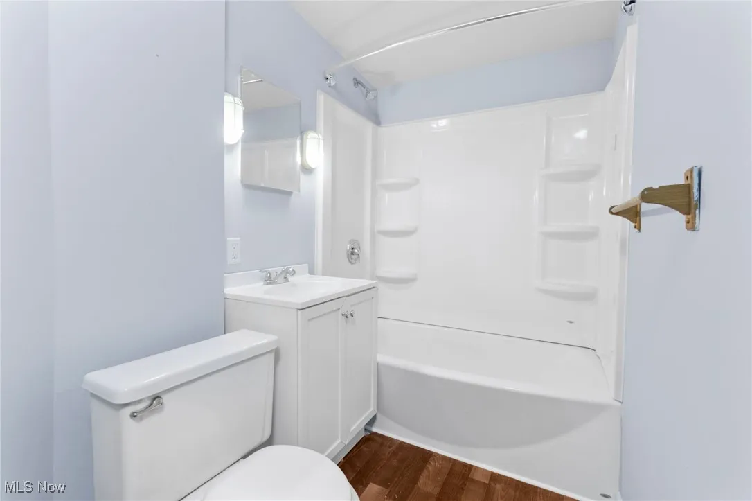 Bathroom featuring wood finished floors, shower / washtub combination, and vanity
