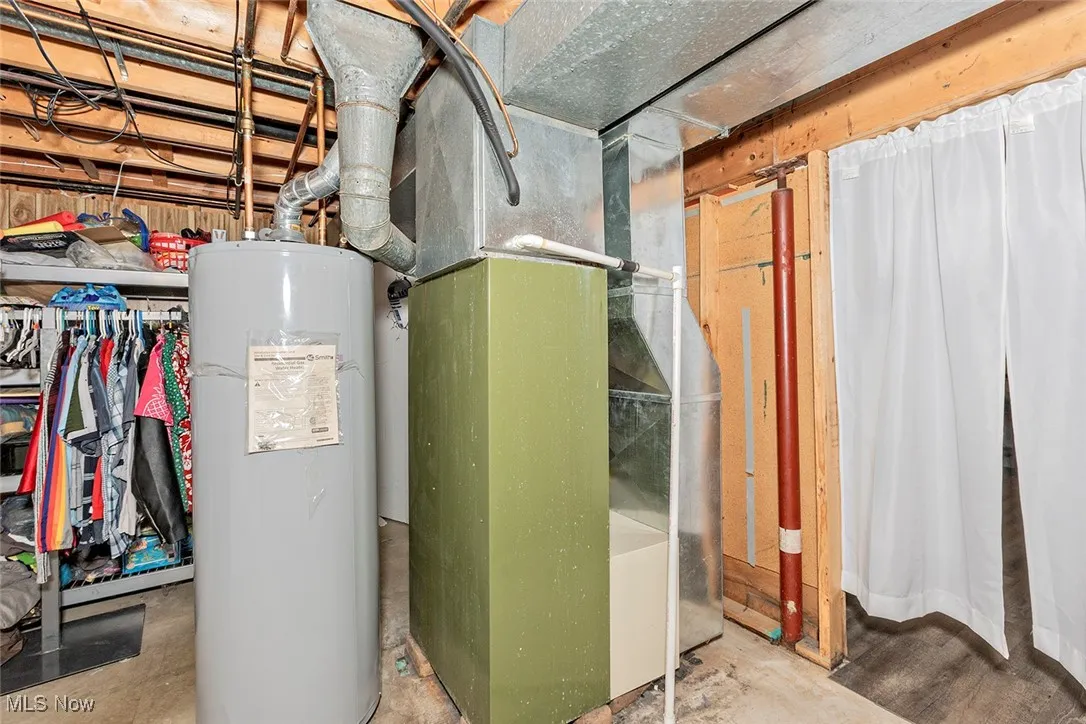 Utility room featuring water heater and heating unit