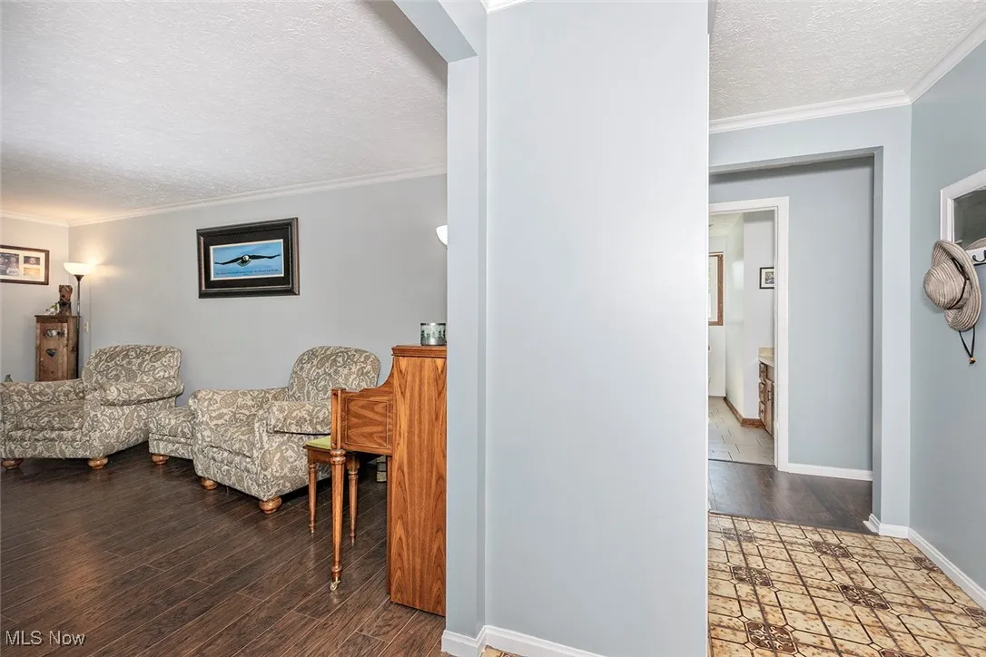 Sitting room featuring ornamental molding, a textured ceiling, and wood finished floors