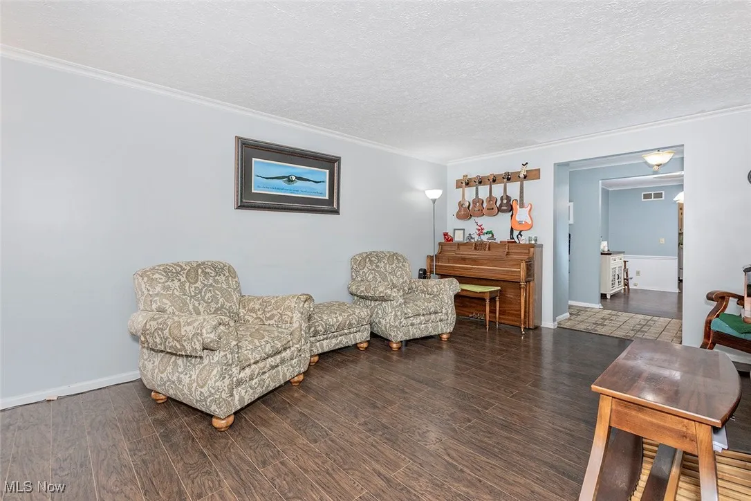 Sitting room with crown molding, wood finished floors, and a textured ceiling