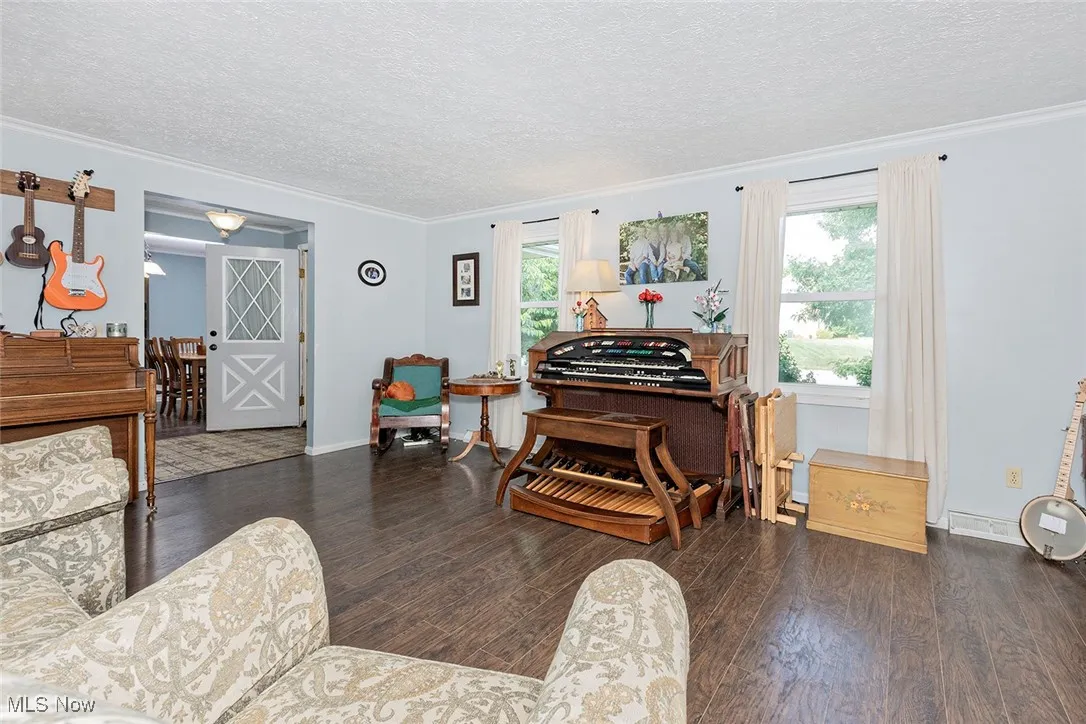Living area with crown molding, wood finished floors, and a textured ceiling