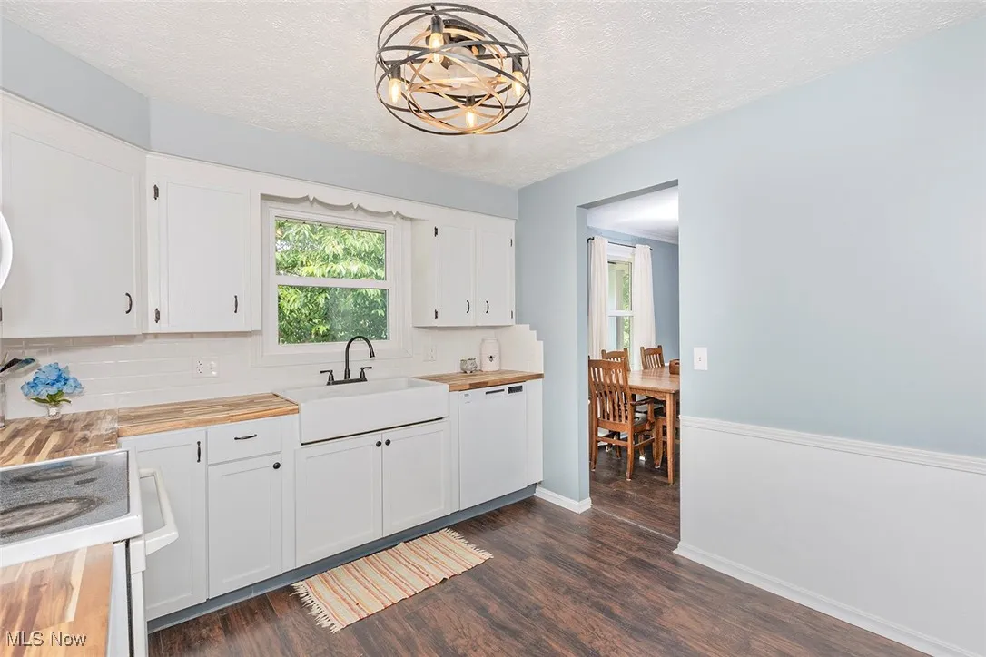 Kitchen with wood counters, a textured ceiling, healthy amount of natural light, and white appliances