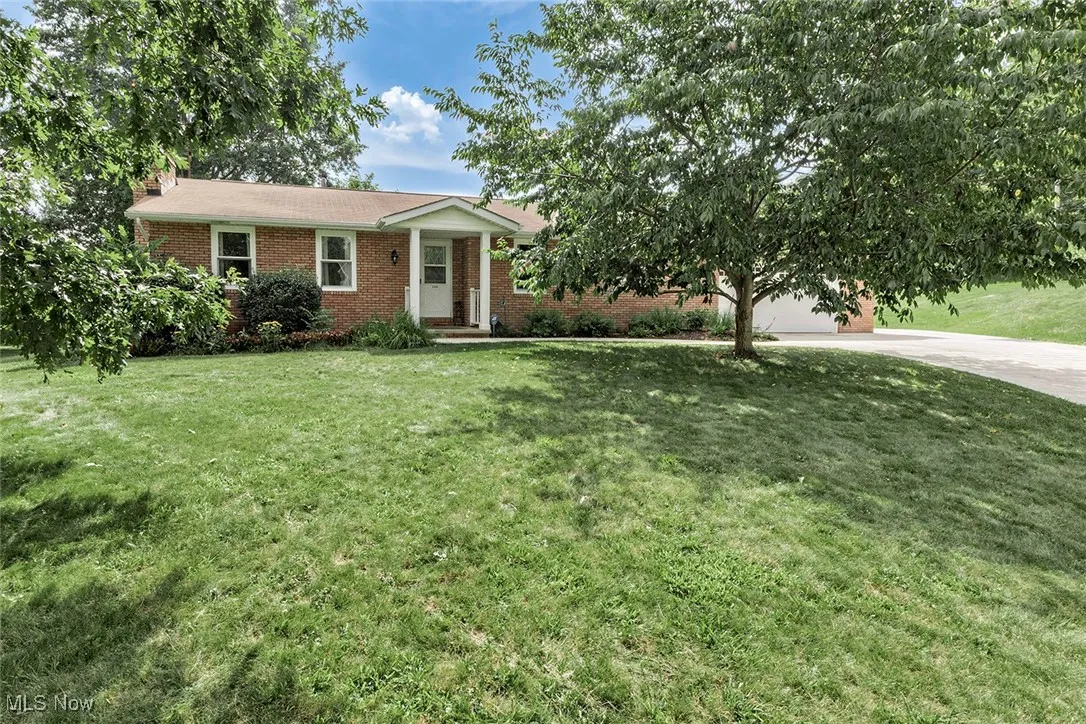 Ranch-style home with concrete driveway, brick siding, a front lawn, and a garage
