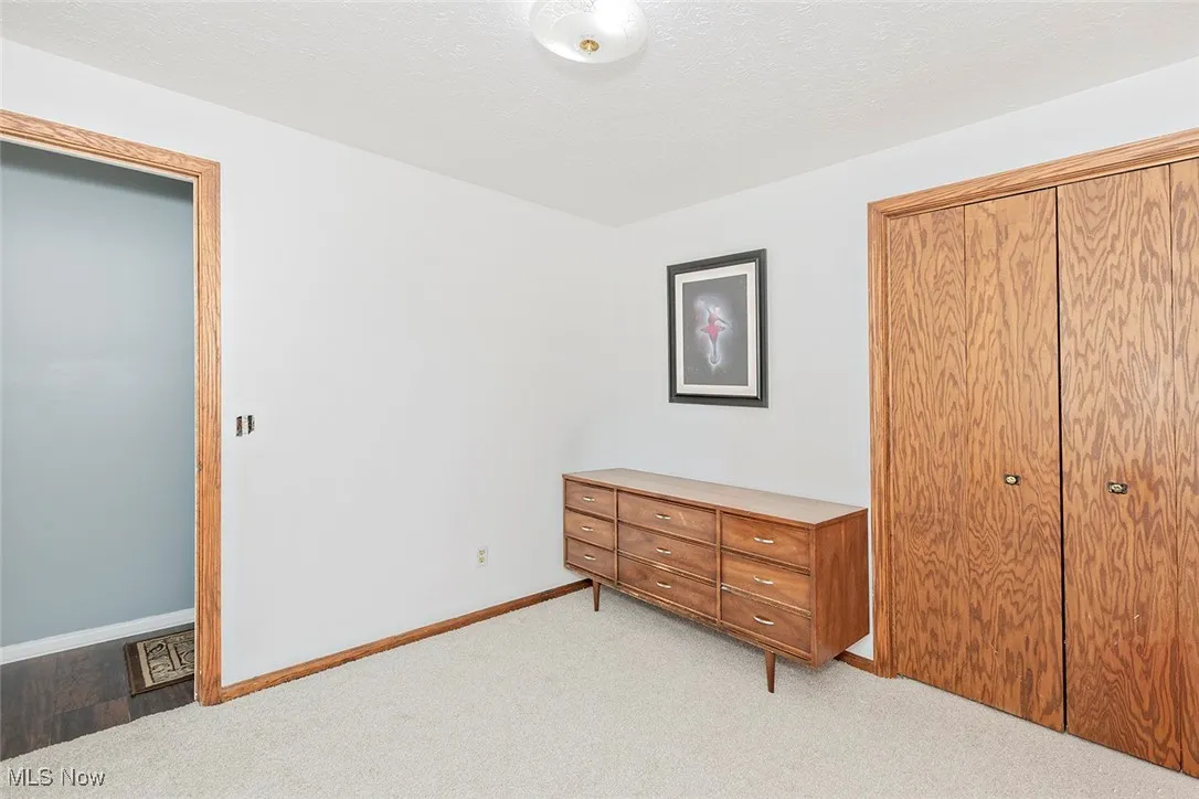 Bedroom with light colored carpet, a textured ceiling, and a closet