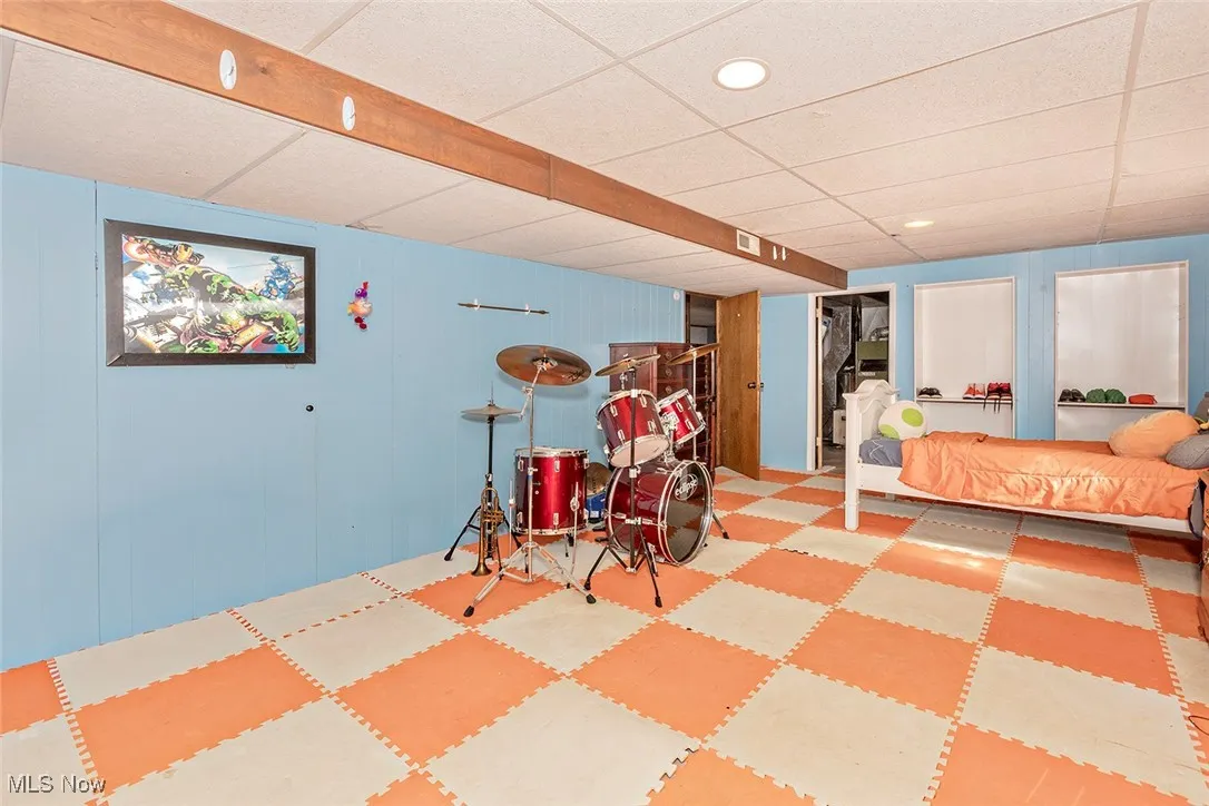 Bedroom with a paneled ceiling, recessed lighting, wooden walls, and tile patterned floors