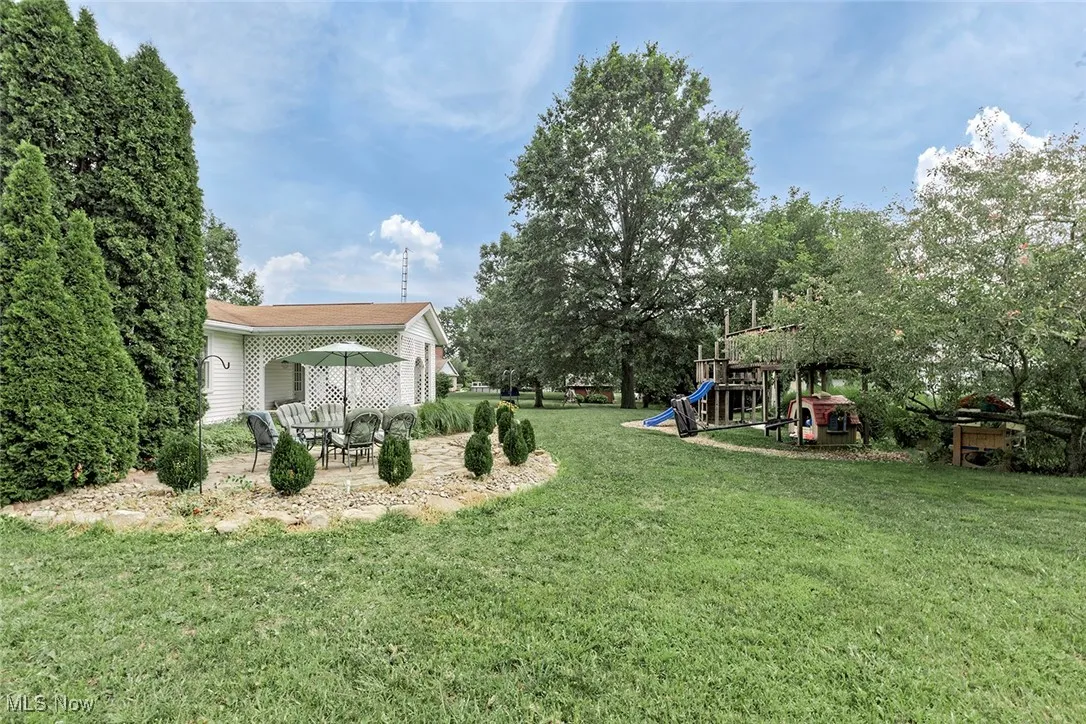 View of green lawn with a playground and a patio area