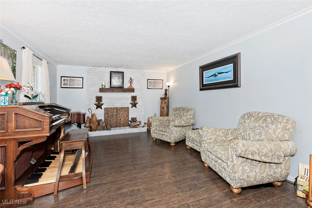 Living area with ornamental molding, wood finished floors, a textured ceiling, and a fireplace