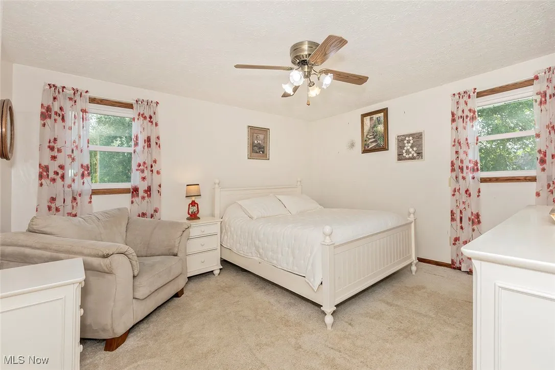 Bedroom featuring light colored carpet, a textured ceiling, and a ceiling fan