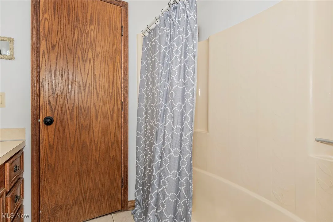 Bathroom featuring vanity, shower / tub combo with curtain, and tile patterned flooring