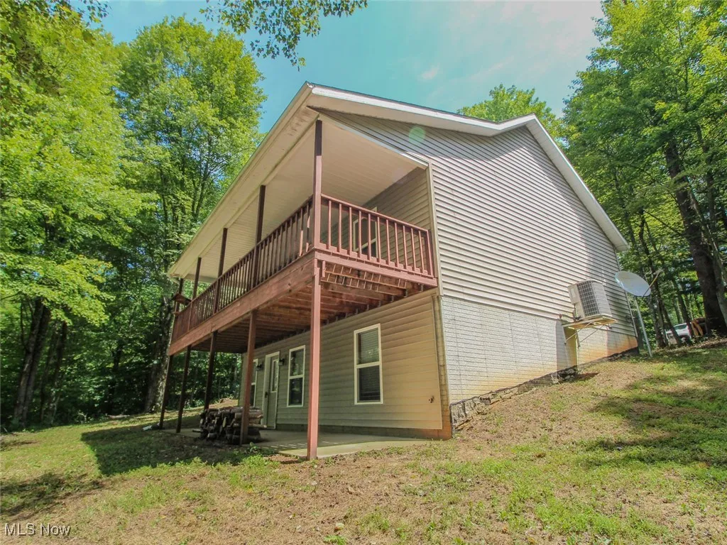 Back of house featuring a lawn, a wooden deck, and a patio area