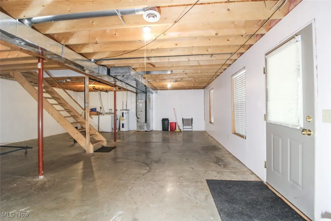 Basement with stairs, washing machine and dryer, heating unit, and electric water heater