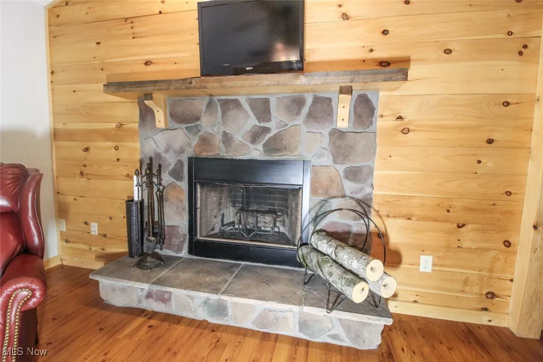 Detailed view of wood finished floors, a stone fireplace, and wooden walls