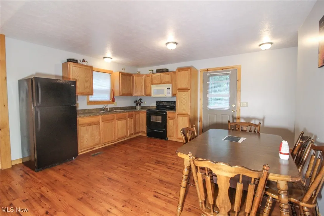 Kitchen featuring black appliances, plenty of natural light, dark wood finished floors, and dark countertops