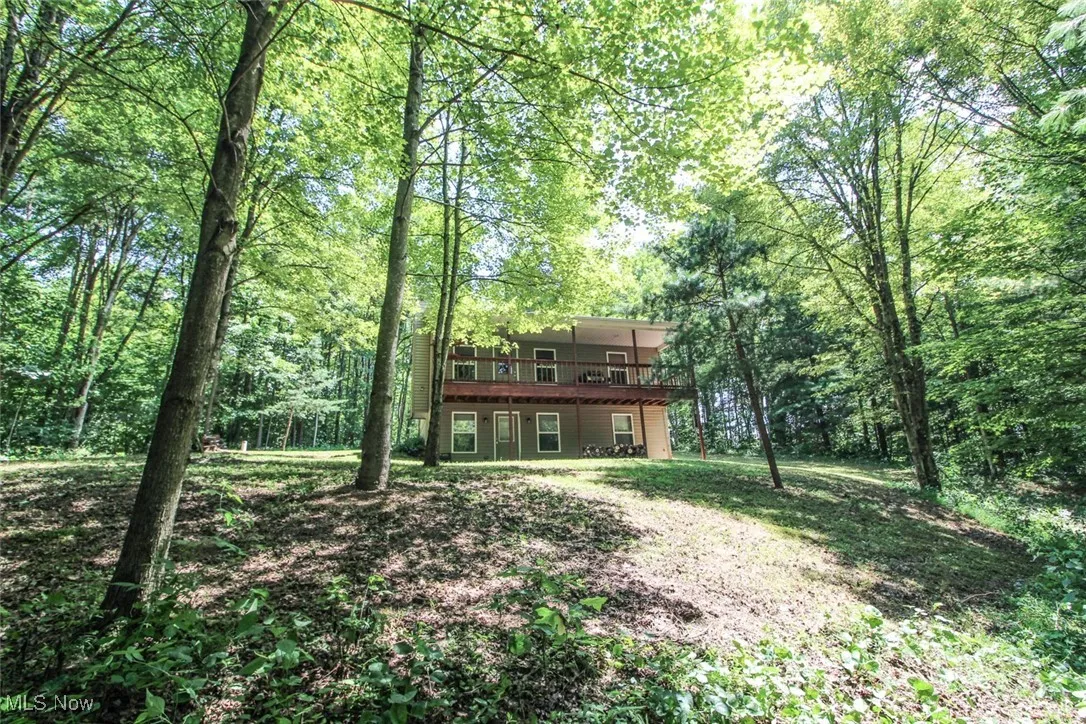 Rear view of house featuring a wooden deck and a forest view