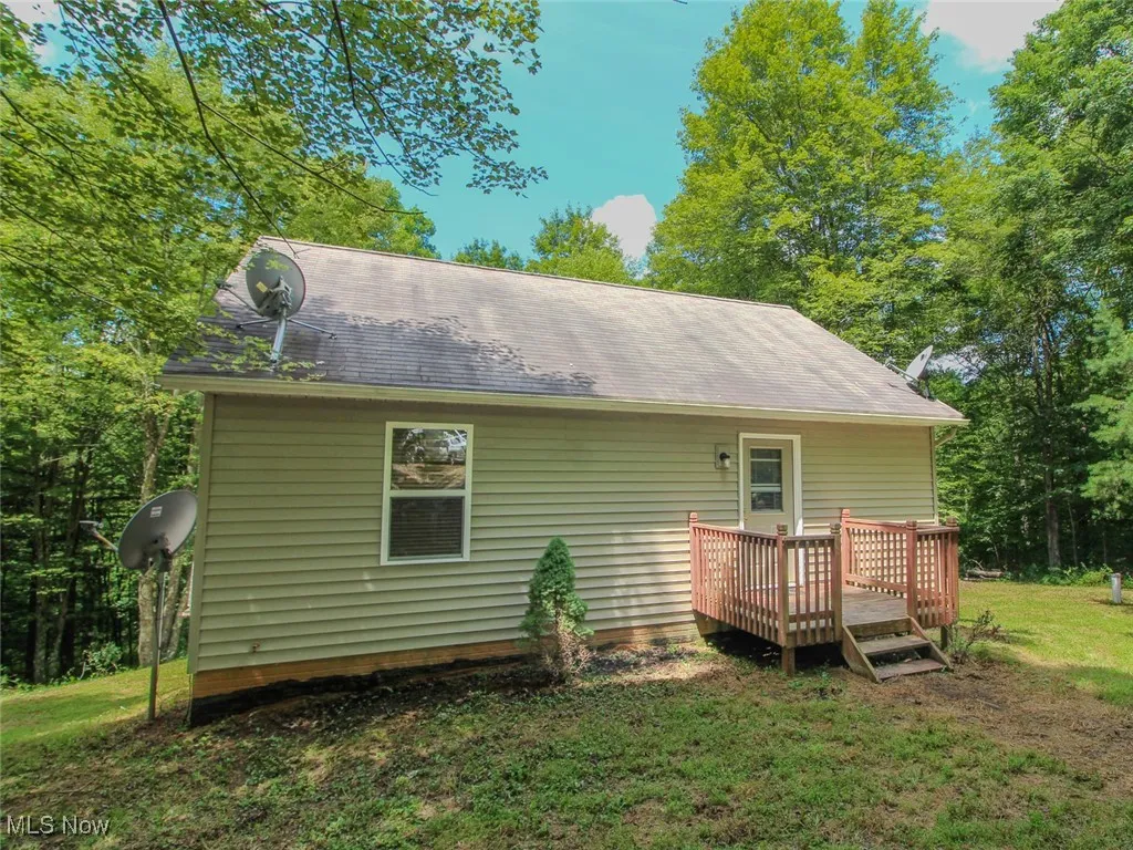 Rear view of property featuring a deck, a yard, and roof with shingles