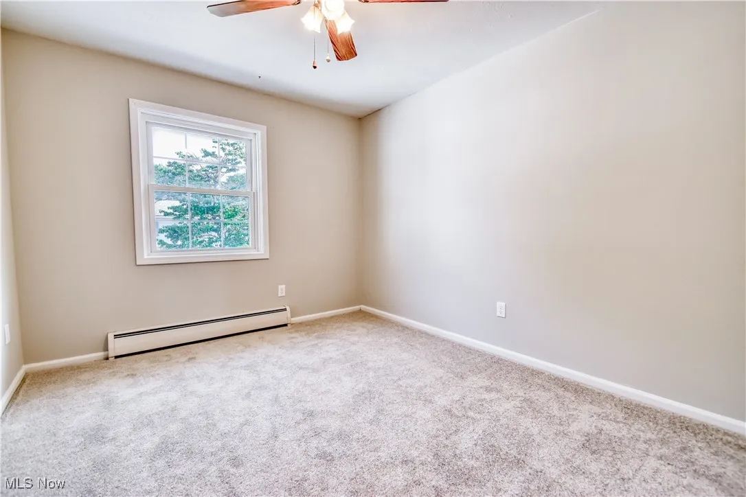 Unfurnished room featuring baseboard heating, carpet, and a ceiling fan