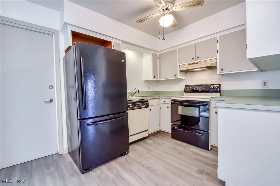 Kitchen with freestanding refrigerator, electric stove, a ceiling fan, and light countertops