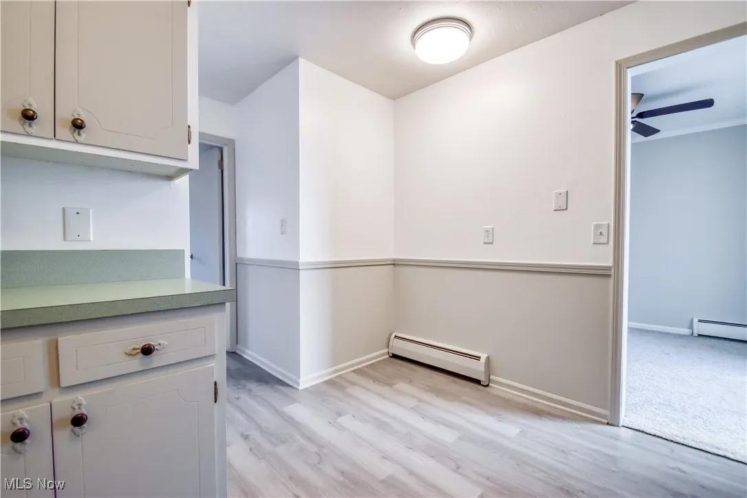 Kitchen with light wood-style flooring, a baseboard radiator, and light countertops