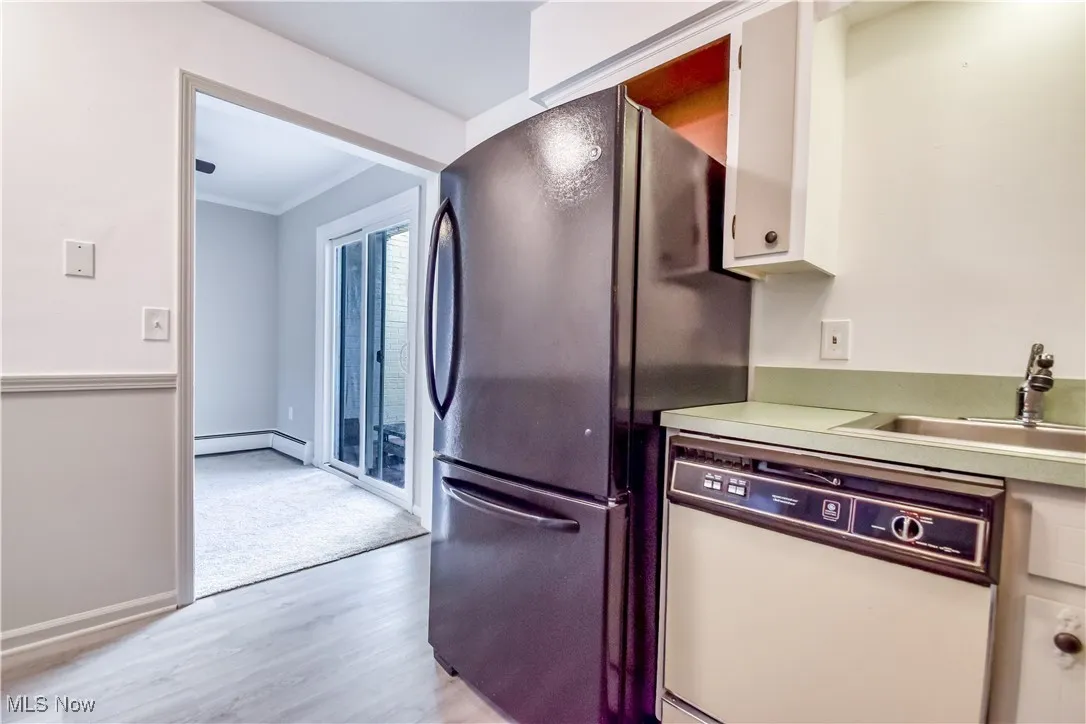 Kitchen featuring dishwasher, light wood-style floors, crown molding, light countertops, and freestanding refrigerator