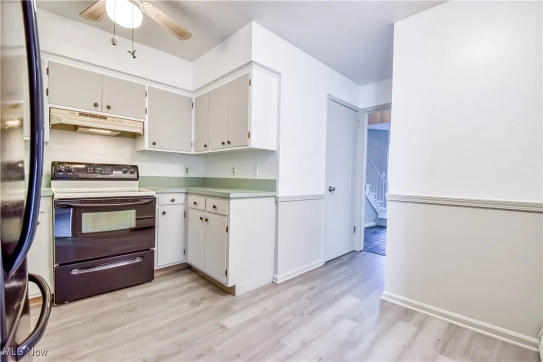Kitchen with electric stove, stainless steel fridge with ice dispenser, under cabinet range hood, a ceiling fan, and light countertops