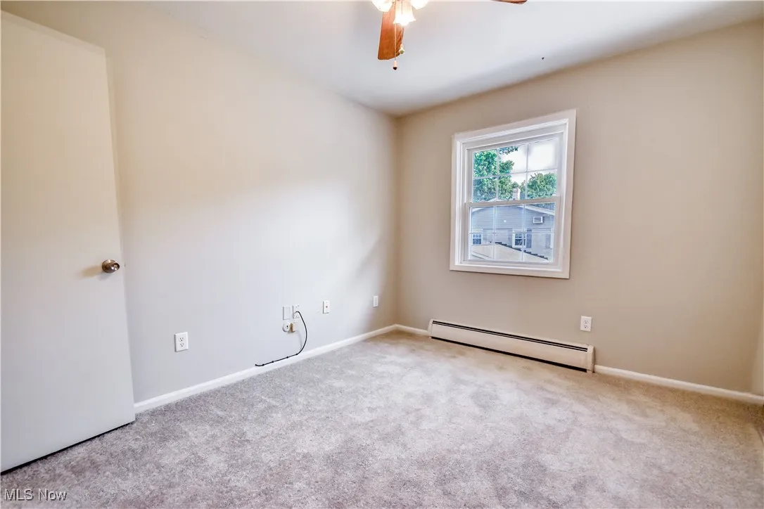 Spare room featuring baseboard heating, carpet flooring, and a ceiling fan