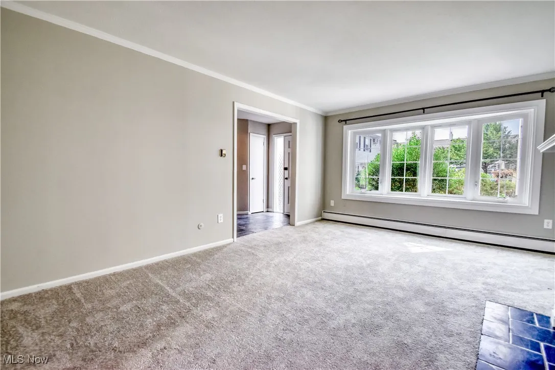 Unfurnished room with ornamental molding, carpet floors, and baseboard heating