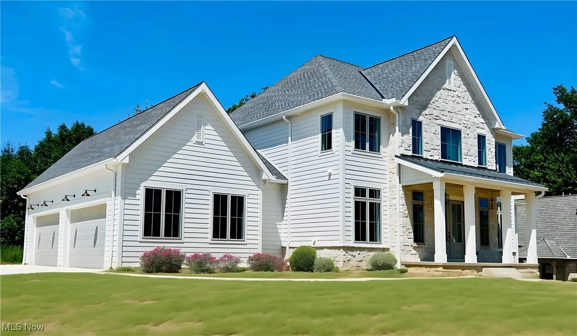 View of front of property featuring covered porch, a front yard, and an attached garage