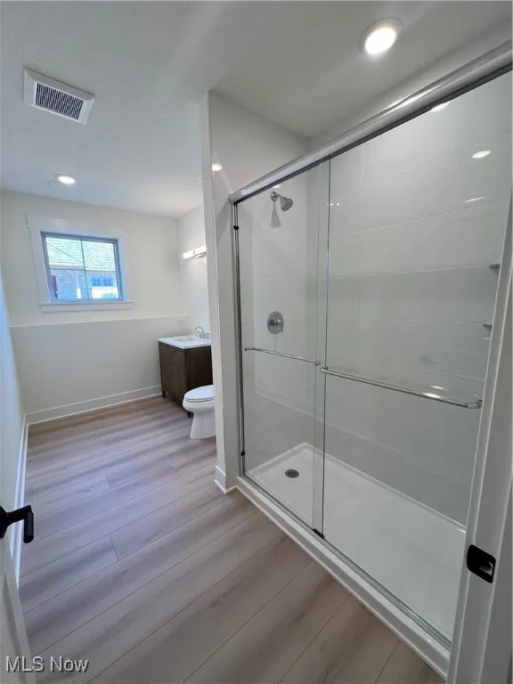 Full bathroom featuring a shower stall, wood finished floors, vanity, recessed lighting, and a textured ceiling