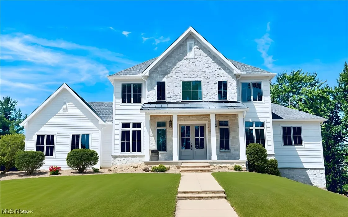 View of front of property featuring french doors, stone siding, a shingled roof, and a front yard