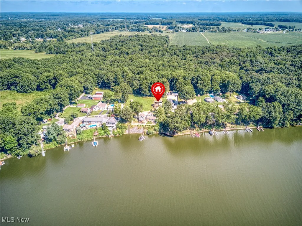 Aerial view of property and surrounding area with a heavily wooded area and a nearby body of water