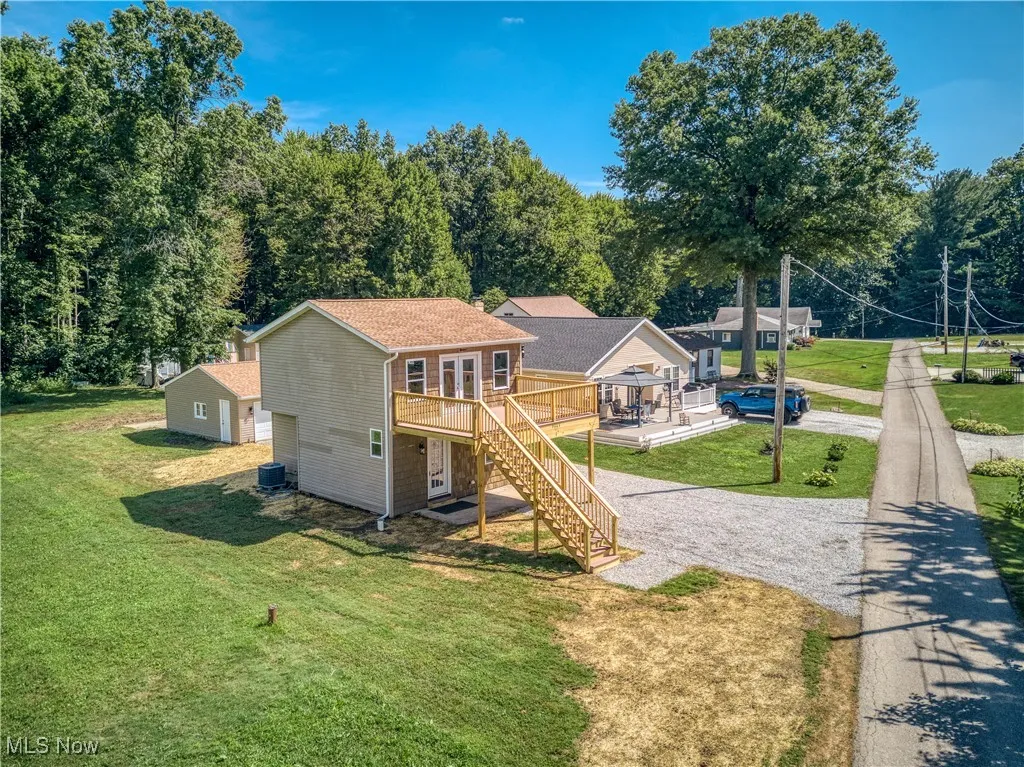 Rear view of property featuring a deck, stairs, and a yard
