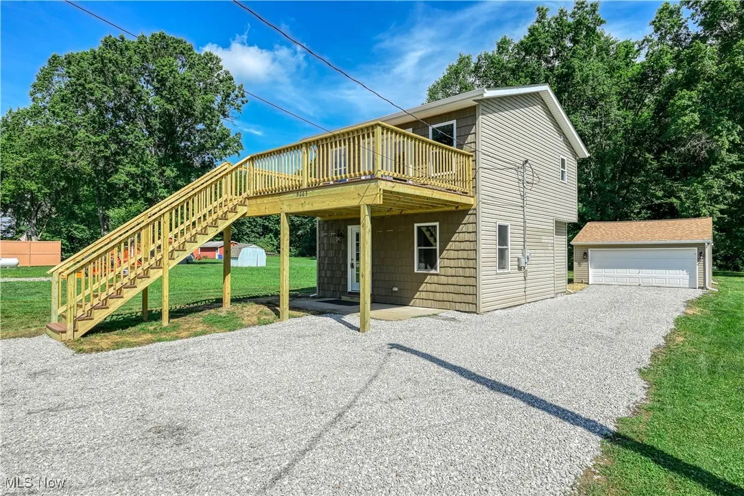 View of front of home featuring an outbuilding, stairs, a wooden deck, and a front yard