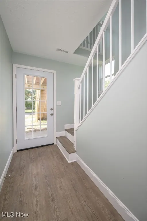 Doorway to outside featuring stairway and wood finished floors