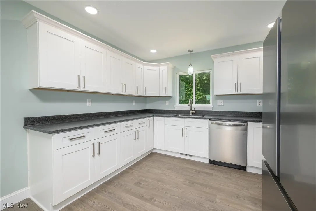 Kitchen featuring stainless steel appliances, light wood-style flooring, white cabinetry, recessed lighting, and dark countertops