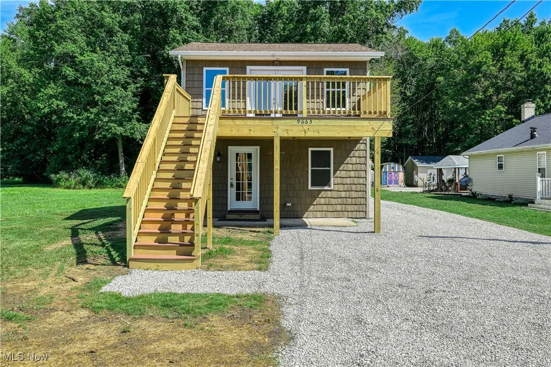 View of front of property with stairway, a wooden deck, and a front lawn