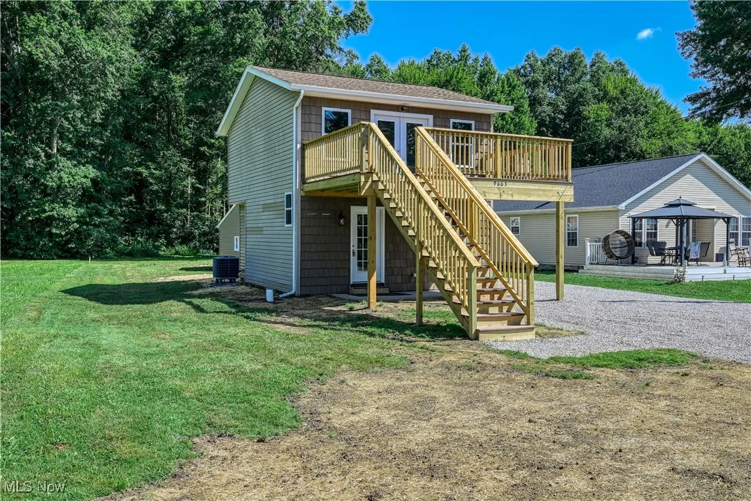 View of front of home with a gazebo, a deck, stairs, and a front lawn