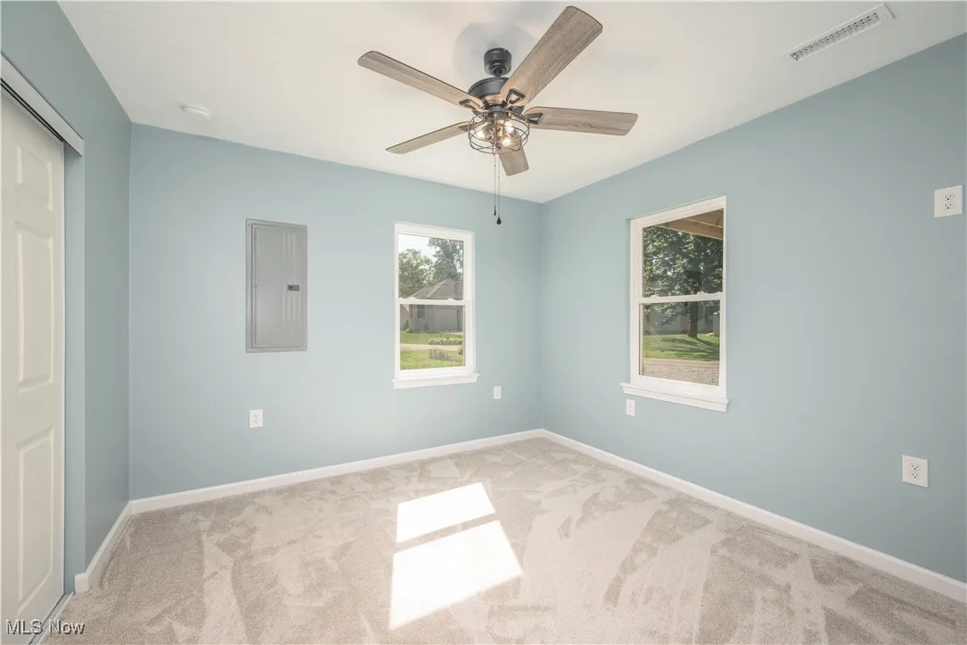 bedroom featuring carpet flooring, electric panel, ceiling fan, and a closet