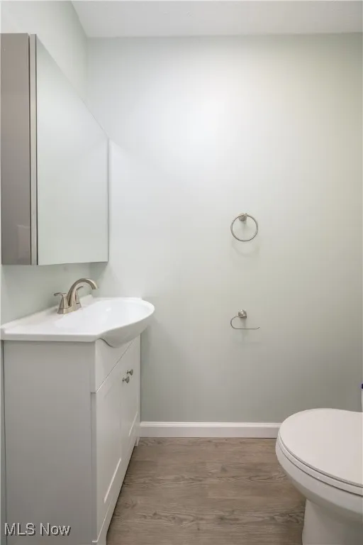 Half bathroom featuring wood finished floors and vanity