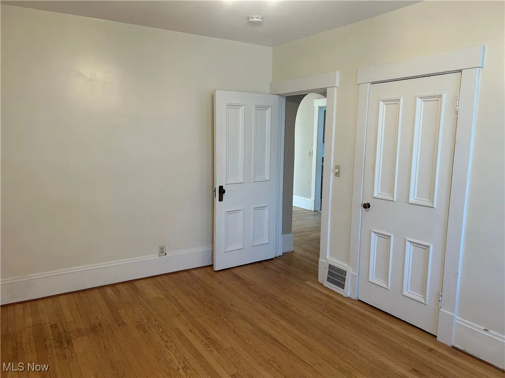 Unfurnished bedroom with light wood finished floors and arched walkways